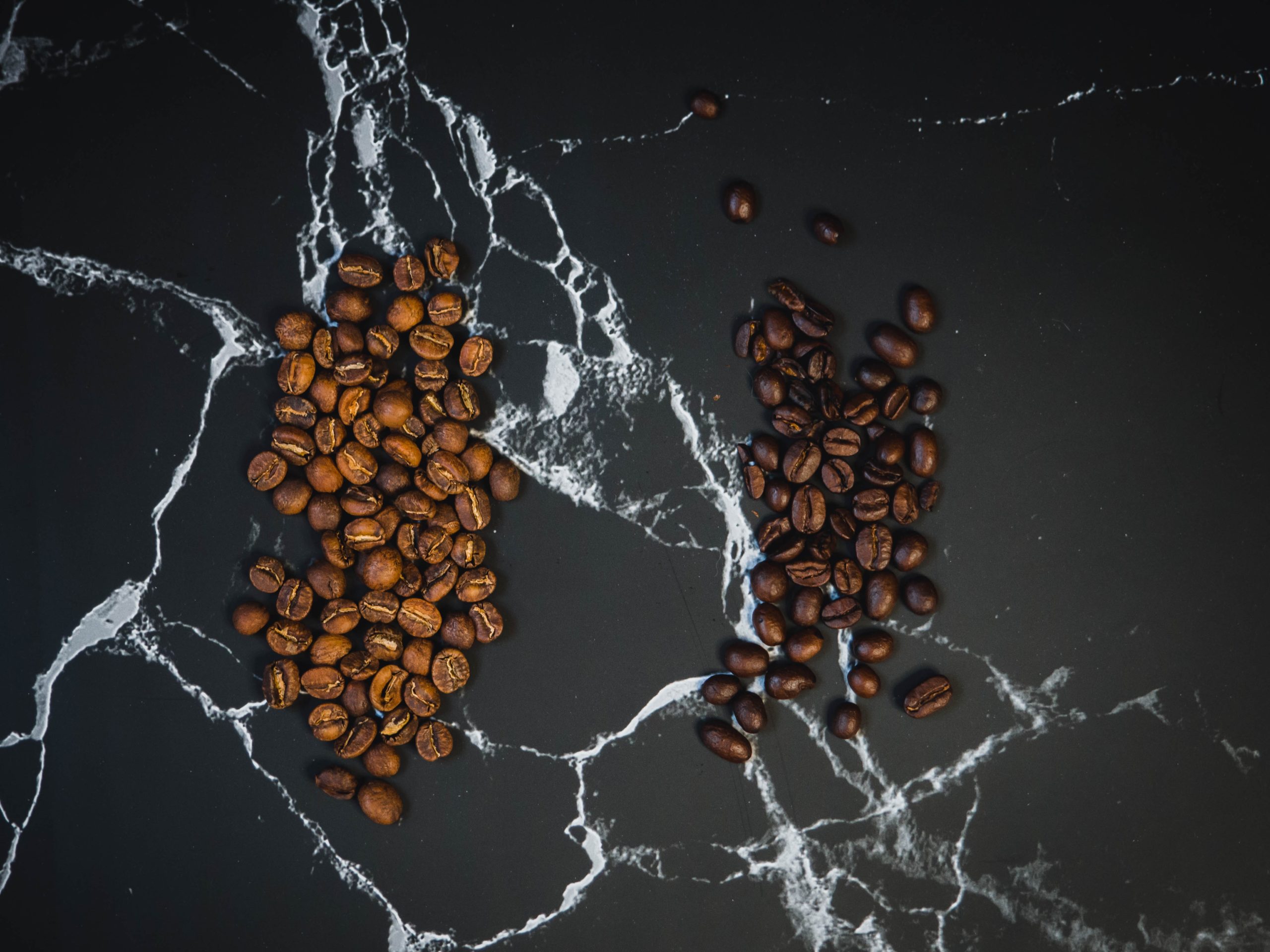 light and dark roast coffee beans placed on a marble table