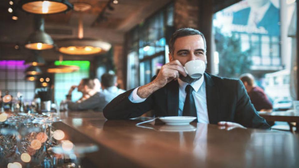 man drinking a cup of coffee in a bar